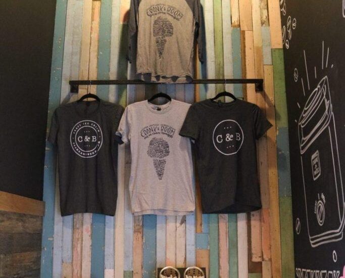 Shirts hanging on multicolored wood wallboard at the Crank & Boom ice cream shop In Manchester
