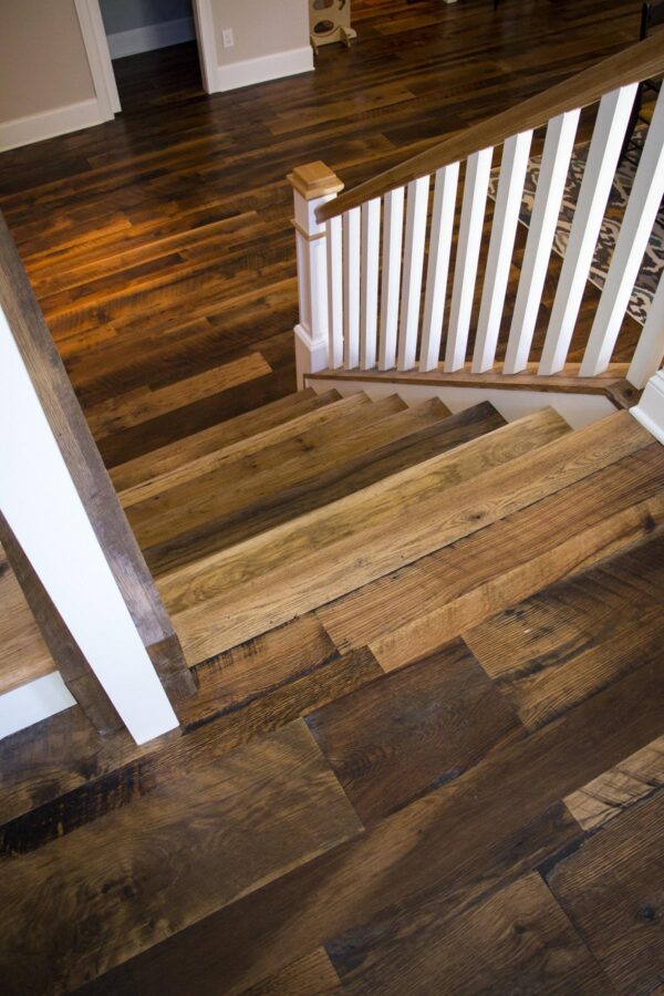 a white staircase with brown reclaimed wood treads on a reclaimed barnwood oak skip-planed solid flooring