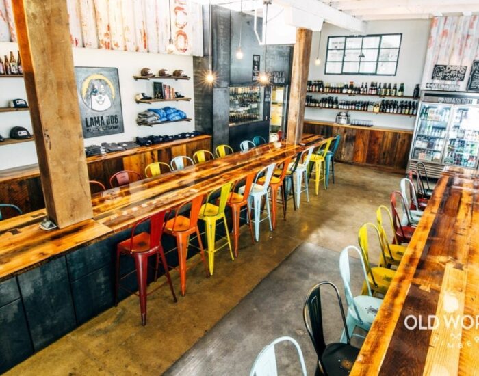 Multicolored chairs and two long reclaimed bar tables at the lama dog Tap Room in Santa Barbara, CA