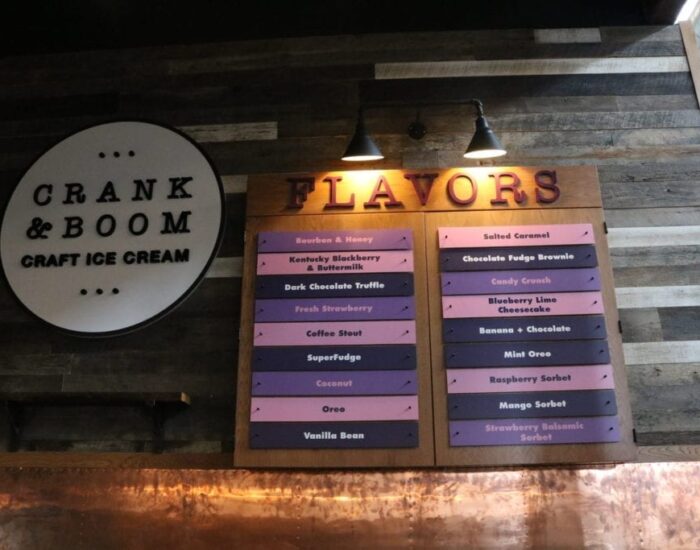 Ice cream flavors menu under two wall lamps on a reclaimed wood wall paneling at the Crank & Boom ice cream shop In Manchester
