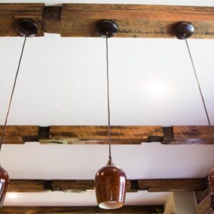 a white ceiling with brown wood beams with three hanging brown lamps