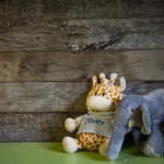 A giraffe and a lion are sitting on a wooden table