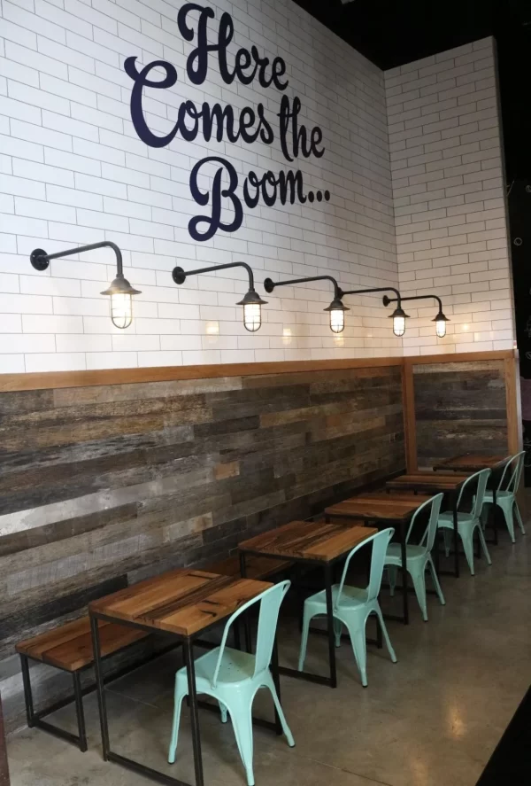 A restaurant with tables and chairs and a sign that says here comes the boom
