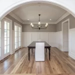 A dining room with a white archway and hardwood floors.