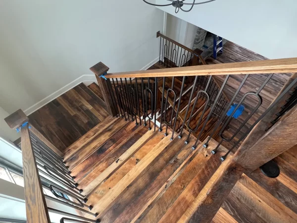 A wooden staircase with a metal railing.