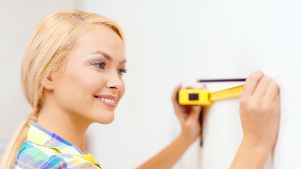 a woman taking measurments on a wall