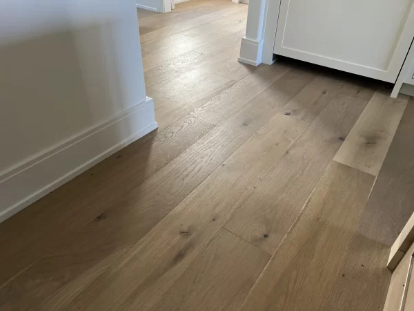 A wooden floor in a kitchen with white cabinets