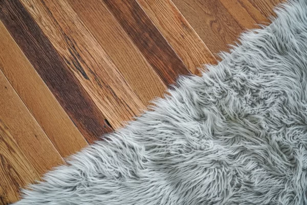 A grey fur rug on a wooden floor