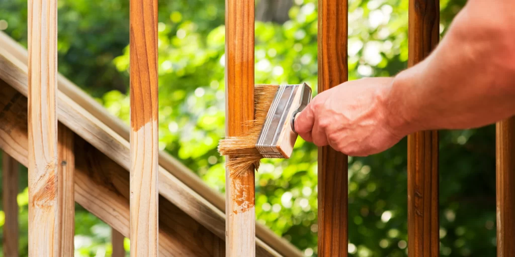 applying wood finish on a fence
