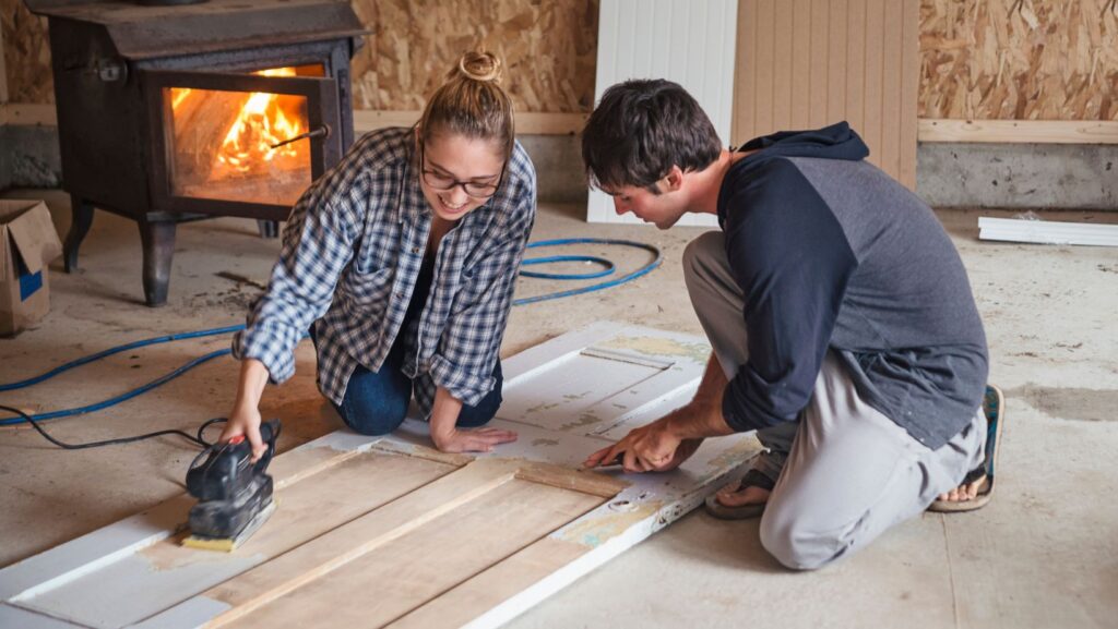 two persons sanding wood door