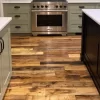 Industrial oak engineered flooring with deep character marks featured in a modern kitchen with sage green cabinetry and marble countertops.