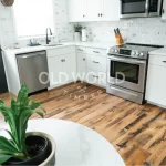 Reclaimed engineered oak floors bringing contrast and history to a kitchen with white cabinetry, subway tile backsplash, and stainless steel appliances.