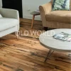 Historic industrial oak floor with visible nail holes and aged textures installed in a warm living area with mid-century modern furniture.