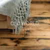 Close-up of Industrial Oak engineered flooring showing rustic character marks and weathered texture beneath a woven gray throw.