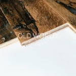 Detailed view of tongue and groove profile of reclaimed engineered oak planks with industrial wear, layered plywood core visible.