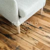 Reclaimed engineered oak flooring with blackened saw marks beneath a beige armchair, reflecting its industrial past.