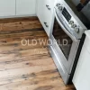 A reclaimed Industrial Oak Engineered floor with vintage charm installed under a stainless steel oven in a white shaker kitchen.