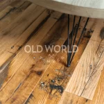 Authentic reclaimed oak flooring planks showing original saw marks and bolt holes, emphasizing industrial heritage.