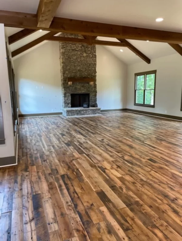 An empty living room with wood floors and a fireplace.