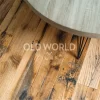 Detailed view of reclaimed Industrial Oak flooring with heavy character marks, under a round wood-and-metal coffee table.
