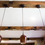 a white ceiling with brown wood beams with three hanging brown lamps