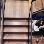 a woman with a laptop sitting under reclaimed custom stair treads