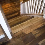 a white staircase with brown reclaimed wood treads on a reclaimed barnwood oak skip-planed solid flooring