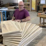 A woodworker in a wood workshop holding uninstalled stair treads