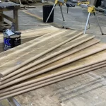 Uninstalled reclaimed wood stair treads placed on a table in a wood workshop