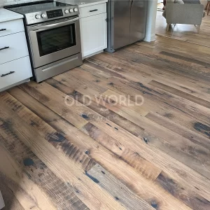 A close-up of Old World Timber’s Heartland Barnwood Mixed Oak engineered reclaimed flooring in a modern white kitchen with stainless steel appliances.