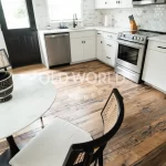 Bright modern farmhouse kitchen with natural light showcasing Heartland Barnwood Mixed Oak engineered reclaimed flooring with rustic charm.