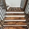 Staircase clad with Heartland Barnwood Mixed Oak engineered reclaimed wood flooring, showcasing rustic tones and black iron railings.