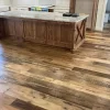 Wide view of Heartland Barnwood Mixed Oak engineered reclaimed flooring in a rustic kitchen with large wood island and granite countertop.
