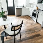 Wide view of Heartland Barnwood Mixed Oak engineered reclaimed flooring in a rustic kitchen with large wood island and granite countertop.
