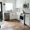 Corner kitchen view showing white cabinetry, stainless appliances, and reclaimed mixed oak flooring with historic texture.