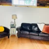 Bright living room featuring reclaimed Douglas Fir clean vertical grain engineered flooring, paired with dark leather sofa and accent chair under natural light.