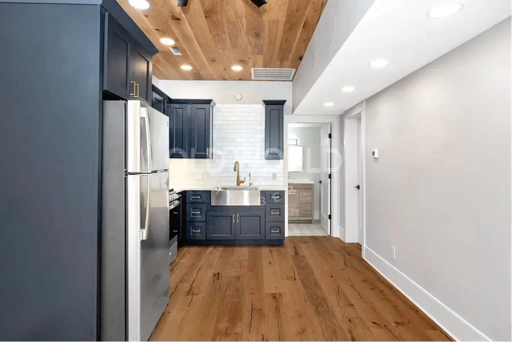 Elegant kitchen with navy cabinets and Modern Harvest engineered oak flooring and ceiling, featuring sustainably sourced planks with natural character.