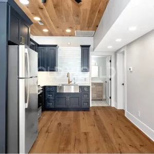 Elegant kitchen with navy cabinets and Modern Harvest engineered oak flooring and ceiling, featuring sustainably sourced planks with natural character.