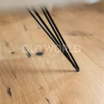 Modern Harvest Oak Flooring shown beneath a black tapered metal table leg, highlighting the reclaimed-style marks and traditional oak texture.