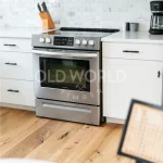 Stainless steel oven and white shaker cabinets set against the natural tones of Modern Harvest engineered oak flooring.