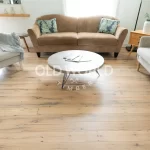 Cozy living room featuring reclaimed white oak engineered flooring with character knots, styled with mid-century modern armchairs and a round coffee table