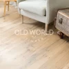 Character-marked reclaimed oak flooring beneath a cozy chair, highlighting blackened nail holes and historic grain patterns.