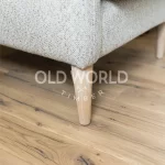Close-up of Industrial Oak Clean Face flooring made from reclaimed hardwood, highlighting organic knots and dark grain streaks under a neutral textured chair.