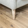 Detailed view of reclaimed white oak engineered flooring featuring natural grain patterns and light distress marks beneath a light gray upholstered armchair.