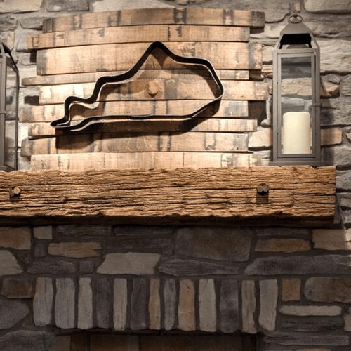 A rustic repurposed wood fireplace mantel with two candle lanterns on it